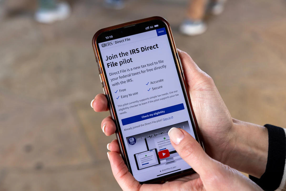 A person holding a phone whose web browser is looking at the IRS's free tax filing website
